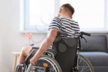 Depressed young man in wheelchair at home�