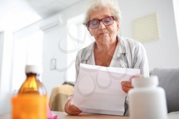 Senior woman reading instruction before taking medicines at home�