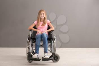 Teenage girl in wheelchair against grey wall�