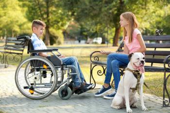 Handicapped boy with his sister and dog resting in park�