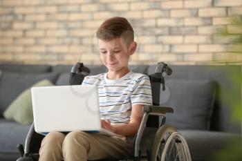 Boy in wheelchair with laptop at home�