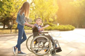Boy in wheelchair and his sister outdoors�