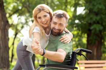 Man in wheelchair with beautiful woman dancing outdoors�