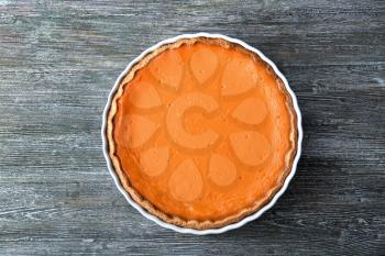 Baking dish with tasty pumpkin pie on wooden table�