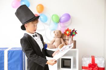Cute little magician with cards indoors�