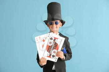 Cute little magician with cards on color background�