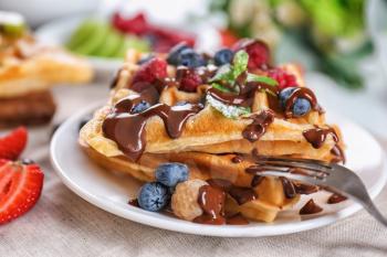 Delicious waffles with berries and chocolate sauce on plate�