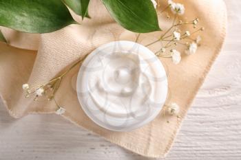Jar with body cream on white wooden table, top view�