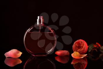 Bottle of perfume with beautiful flower on dark background�