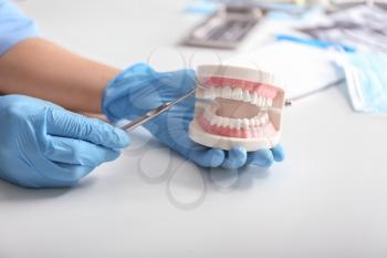Dentist with artificial jaw and dental tool at light table�