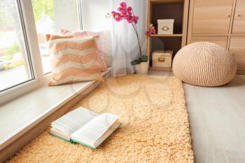 Cozy place for rest with soft pillows and book near window�