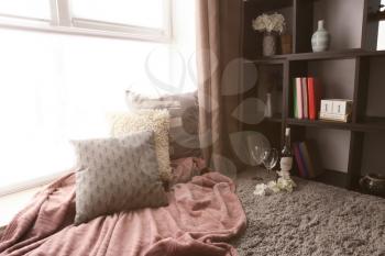 Cozy place for rest with pillows and soft plaid near window in room�
