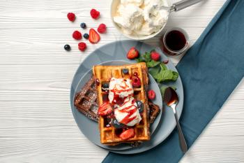 Delicious waffles with berries and ice cream on wooden table�