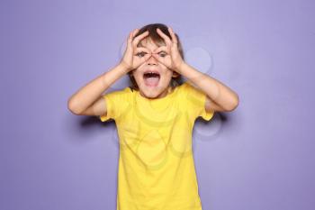 Funny little boy in t-shirt on color background�