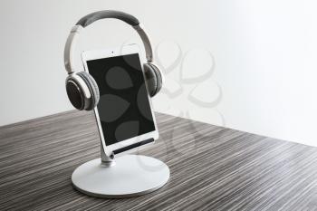 Tablet computer with headphones on wooden table�