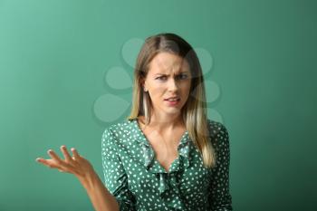 Indignant young woman on color background�