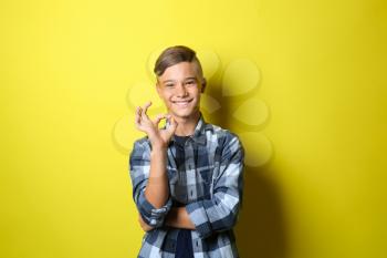 Teenage boy showing OK gesture on color background�