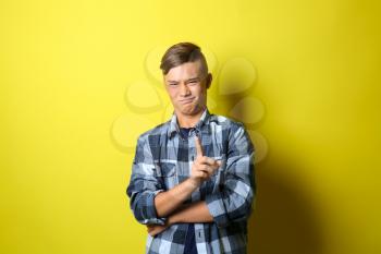 Emotional teenage boy waggling finger at viewer on color background�
