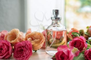 Bottle of perfume with beautiful flowers on white table�