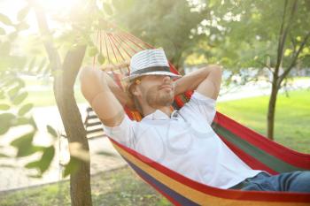 Handsome young man resting in hammock outdoors�