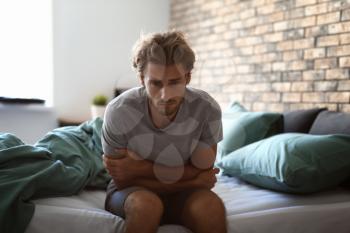 Depressed young man sitting on bed�