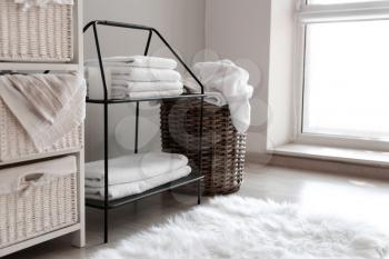 Wicker baskets with dirty laundry and folded clean towels on shelves�