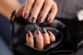Woman with stylish beautiful manicure holding black fabric, closeup�