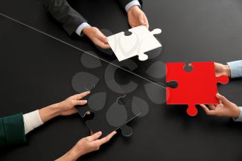 Business team with pieces of puzzle on dark table�