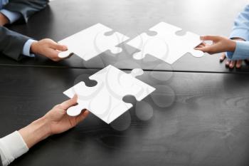 Business team with pieces of puzzle on dark table�