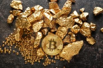 Bitcoin and gold nuggets on table�