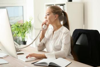 Beautiful female secretary talking on telephone in office�