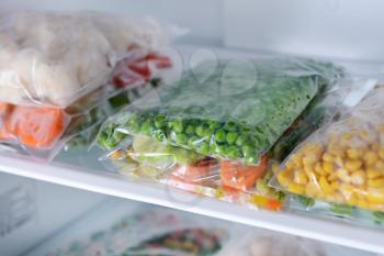 Plastic bags with frozen vegetables in refrigerator�
