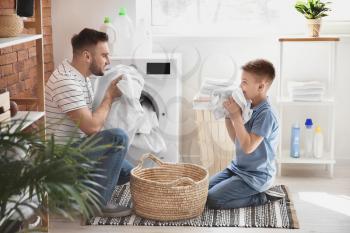 Man and his little son doing laundry at home�