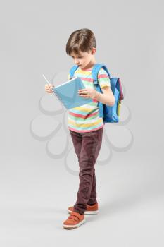 Cute little schoolboy with book on light background�