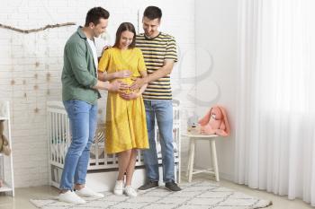 Gay couple with pregnant woman at home�