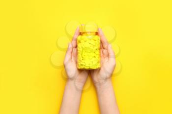 Female hands with pills in bottle on color background�