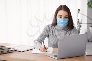 Young woman wearing medical mask while working in office�