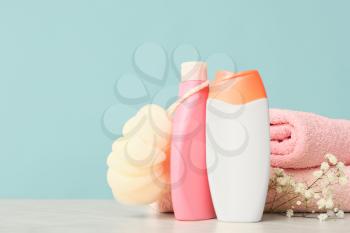Shower gels, towels and loofah on color background�
