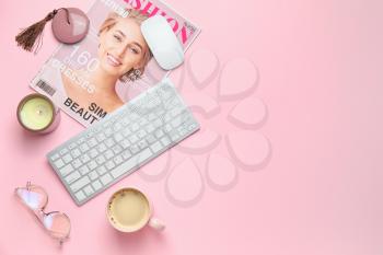 Computer keyboard with candle, fashion magazine and cup of coffee on color background�