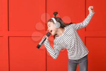 Cute little girl singing against color background�
