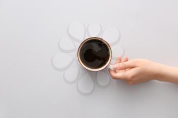 Female hand with cup of hot coffee on light background, top view�