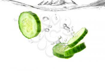 Falling of fresh cucumber slices into water against white background�