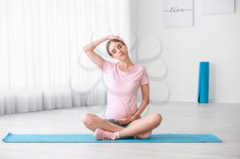 Sporty young pregnant woman training at home�