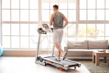 Young man training on treadmill at home�