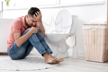 Young man suffering from anorexia near toilet bowl at home�