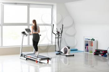 Sporty young woman training on treadmill in gym�