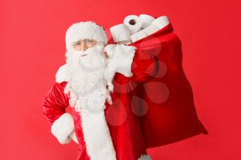 Santa Claus with toilet paper in bag on color background. Concept of coronavirus epidemic�