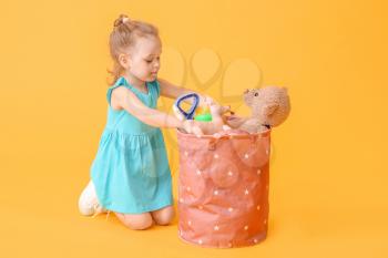Little girl with toys on color background�