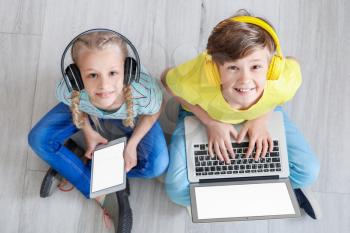 Cute little children with laptop and tablet at home. Concept of online education�