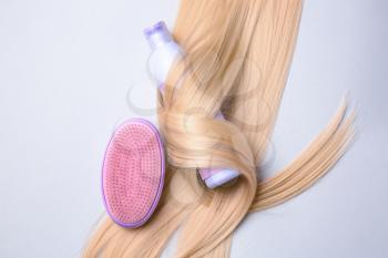 Bottle of shampoo for blonde hair and brush on light background�